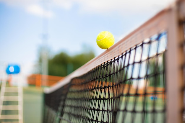 Balle de tennis jaune verdâtre vif frappant le filet