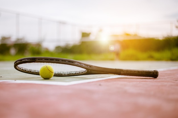 Balle de tennis et raquette sur terrain dur sous la lumière du soleil