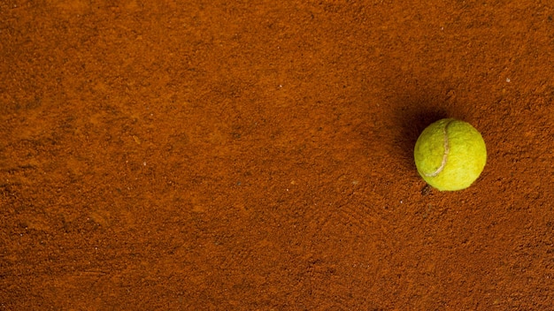 Balle de tennis sur le sol orange dans un court de tennis