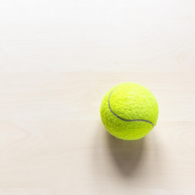 Balle de tennis sur une table en bois marron clair