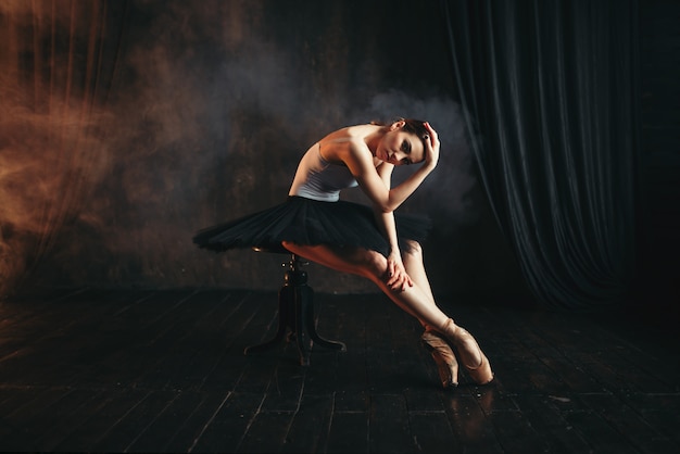 Ballerine assise sur une banquette noire au théâtre