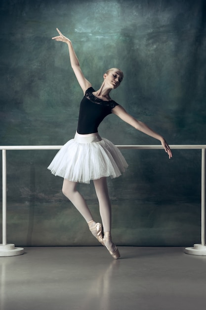 La ballerine classique posant à la barre de ballet