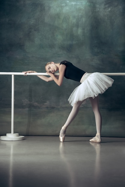 La ballerine classique posant à la barre de ballet