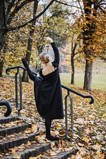 Ballerine dansant dans la rue de la ville d'automne danseuse de ballet moderne en robe noire chaussures de pointe à l'extérieur