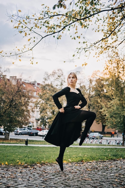 Ballerine dansant dans la rue de la ville d'automne danseuse de ballet moderne en robe noire chaussures de pointe à l'extérieur