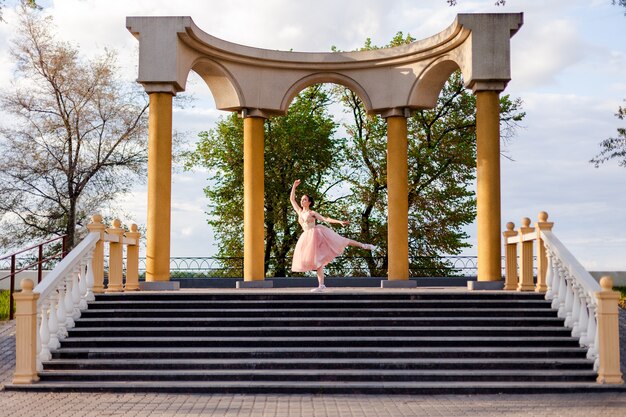 Une ballerine danse la jambe levée dans un arc de colonnes en architecture urbaine sur le remblai...