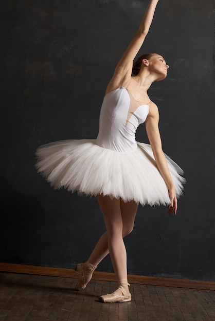 Ballerine de femme dans la danse de grâce de représentation de tutu blanc