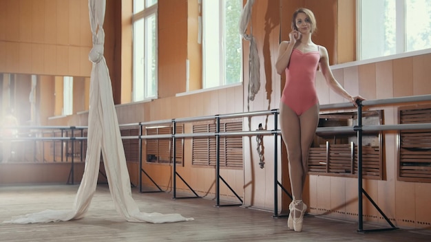 Ballerine fille parle par téléphone dans une salle de danse, grand angle