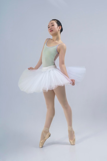 Une ballerine japonaise pose dans un studio photo avec des éléments de ballet montrant l'étirement et la plasticité