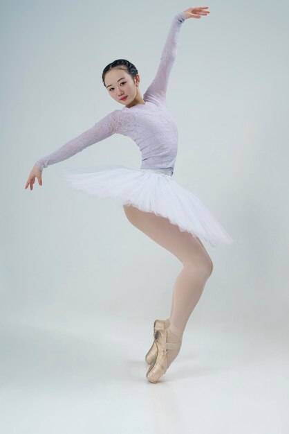 Une ballerine japonaise pose dans un studio photo avec des éléments de ballet montrant l'étirement et la plasticité