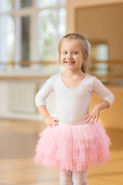 Ballerine petite fille debout près du miroir dans la salle de sport