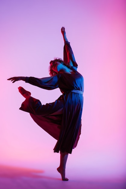 Ballerine professionnelle dansant le ballet dans une fumée. Femme en body noir sur fond de projecteurs.