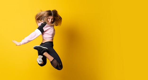 Ballerine urbaine danser sur fond jaune isolé et sauter