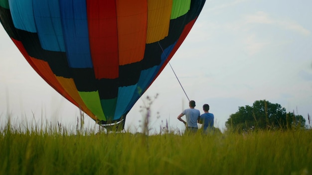 Photo ballon à air chaud coloré sur le terrain d'été au coucher du soleil, grand angle