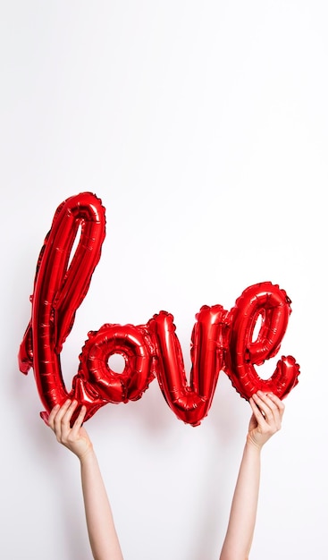 Ballon d'amour feuille rouge tenu contre un arrière-plan uni, blanc