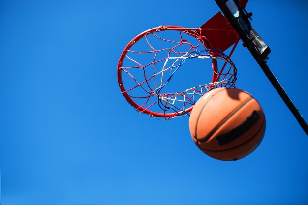 Ballon de basket-ball et cerceau isolés sur ciel bleu