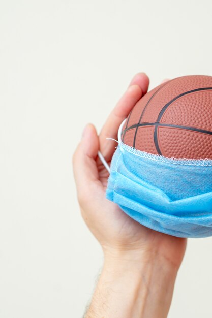 Ballon de basket avec masque médical dans les mains de l'homme