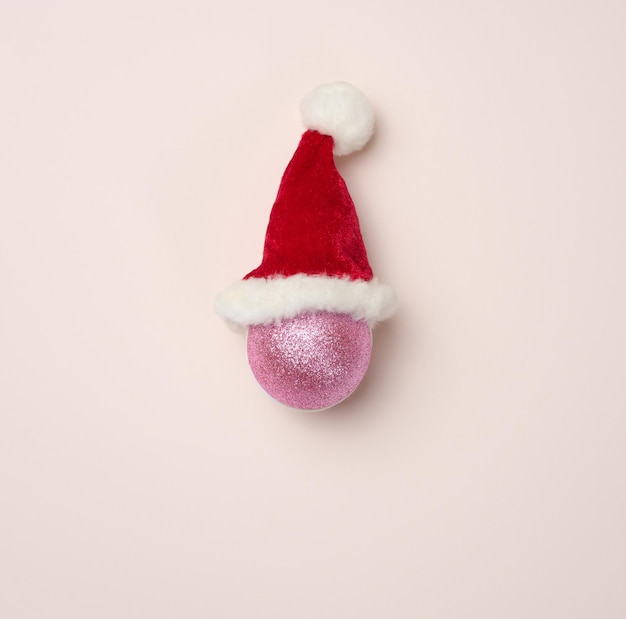 Ballon brillant rose dans un bonnet rouge sur un décor de Noël de fond beige