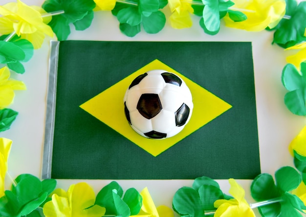 Ballon de football de coupe du monde sur le dessus du drapeau brésilien sur le fond blanc