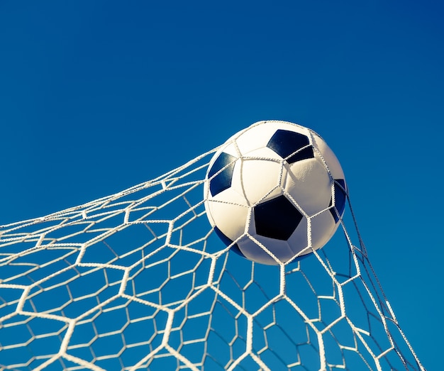 ballon de football dans le but net avec un ciel bleu