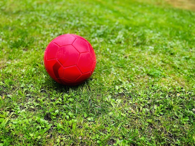 Ballon de football rouge sur l'herbe verte mise au point sélective