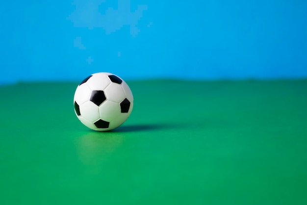 Photo ballon de football sur une surface verte avec un fond bleucontexte pour les concepteurscopier l'espace