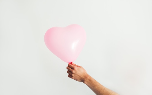 Ballon en forme de coeur gonflable rose à la main Fond blanc