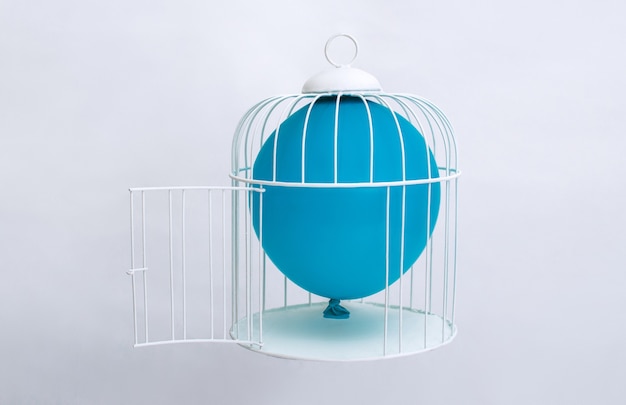 Ballon gonflé à l'intérieur d'une cage à oiseaux représentant l'impossibilité de s'échapper