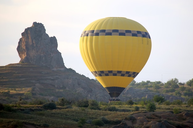 Ballon jaune avec des gens qui volent près du rocher