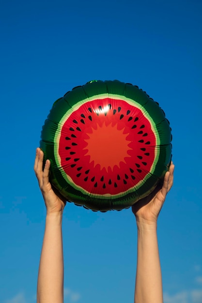 Ballon de pastèque d'été tenu en l'air contre un ciel d'été bleu vif