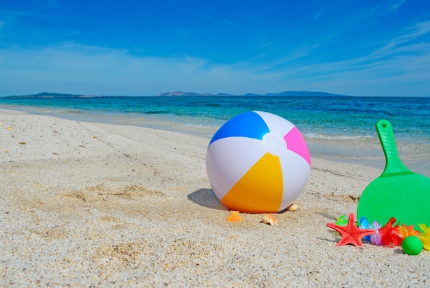 Ballon de plage et raquettes sur un rivage doré