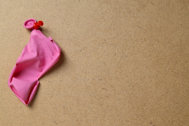 Un ballon rose éclaté épinglé sur un tableau beige pour le texte