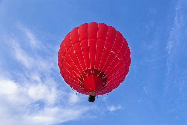 Un ballon rouge vole dans le ciel. Un ballon avec une nacelle repose sur le sol, équipement pour remplir le ballon d'air froid et chaud. Préparation du ballon pour le lancement.