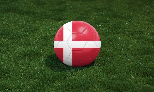Ballon de soccer aux couleurs du drapeau du Danemark dans un stade sur fond d'herbes vertes