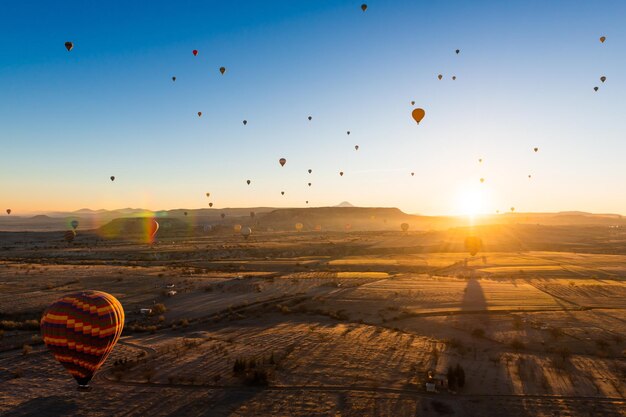 Des ballons à air chaud colorés sur les collines au lever du soleil en Cappadoce, en Turquie