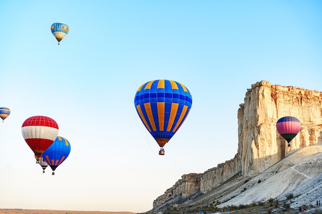 Ballons à air colorés volant dans un ciel clair près d'énormes montagnes blanches aux beaux jours