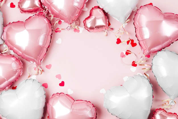 Ballons à air de feuille en forme de coeur sur fond rose pastel. Notion d'amour. Célébration de vacances. Décoration de fête de Saint-Valentin ou de mariage/d'enterrement de vie de jeune fille. Ballon métallique