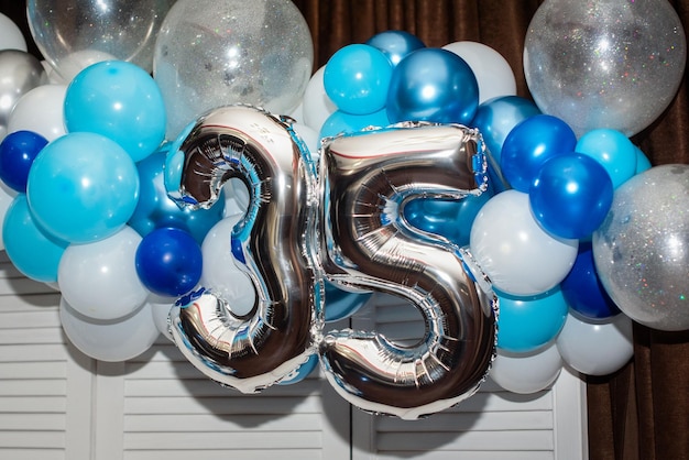 Ballons chiffre Nr. 35 pour anniversaire ou fête d'anniversaire. la fête ou la célébration est décorée de boules bleues et argentées.