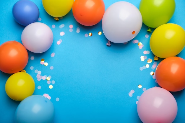 Ballons colorés et confettis sur la vue de dessus de table bleue.