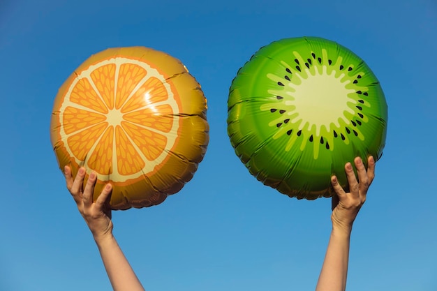 Ballons de fruits d'été tenus en l'air contre un ciel d'été bleu vif