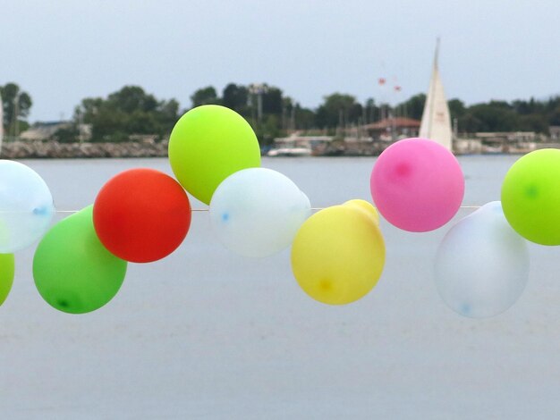 Des ballons multicolores attachés à une corde contre la mer