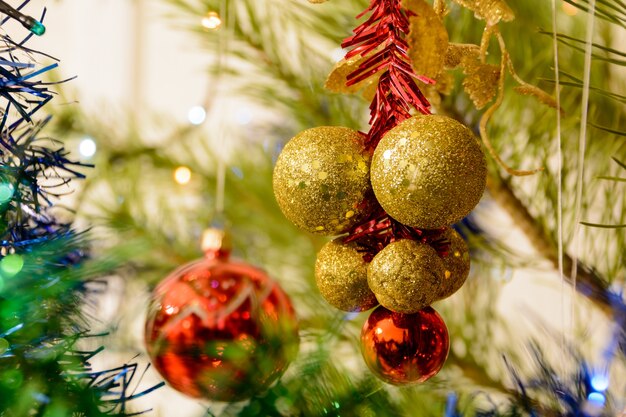 Ballons de Noël colorés sur un arbre de Noël sur fond de guirlandes brillantes. Boules colorées entourées de branches de l'arbre de Noël. Notion de Noël.