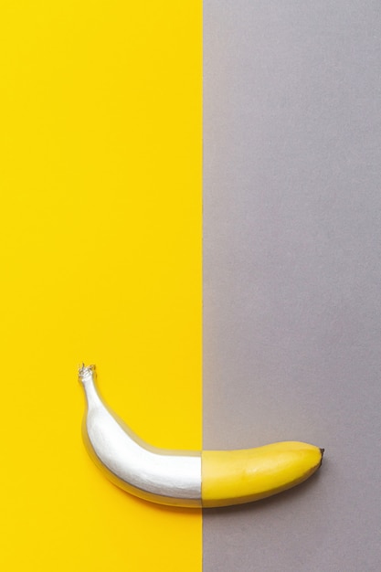 Banane argentée peinte sur un mur jaune et gris