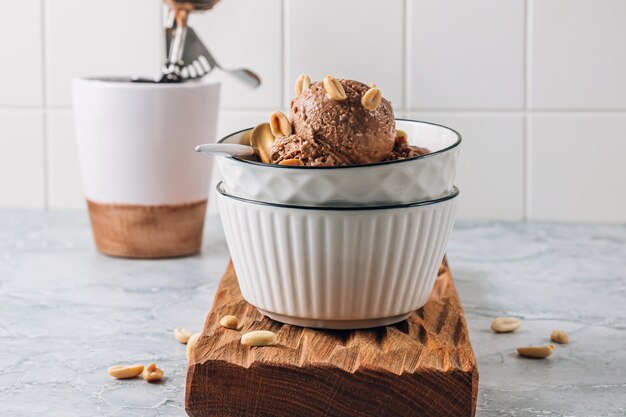 Photo banane au beurre de cacahuète végétalienne maison et crème glacée au chocolat dans un bol avec des cacahuètes sur gris