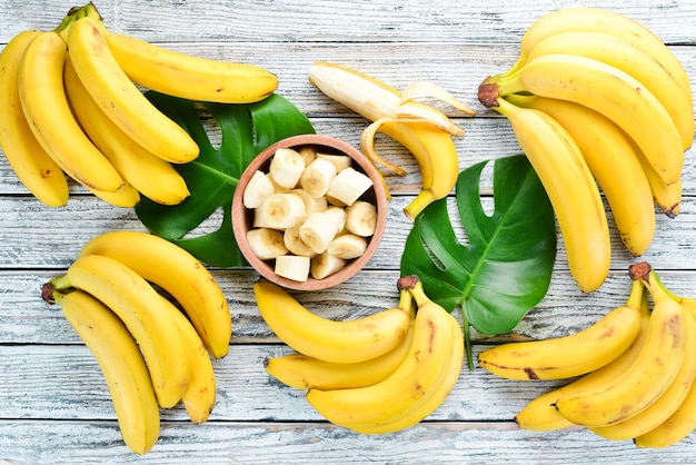 Banane avec des feuilles vertes sur une table en bois blanche Fruits tropicaux Vue de dessus Espace de copie gratuit