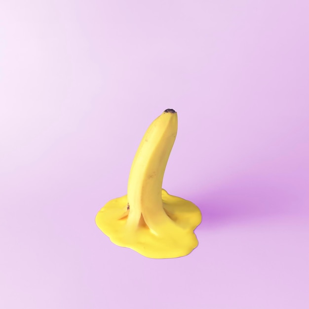 Banane fondant dans une flaque d'eau sur fond violet Concept de fruits d'été