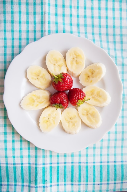 Banane et fraises sur une plaque blanche et une serviette colorée