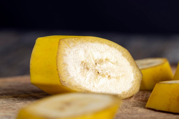 Banane jaune mûre non pelée coupée en morceaux sur une planche