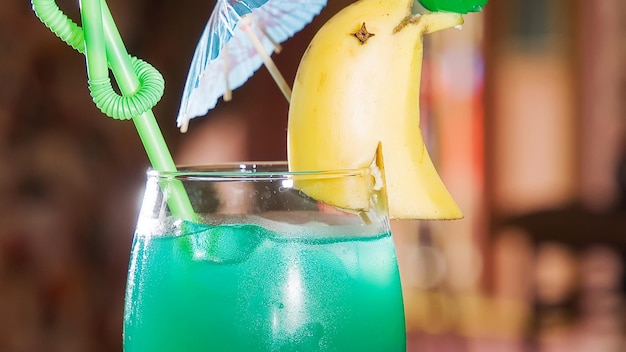 une banane et un kiwi bleu sur un verre avec une paille verte