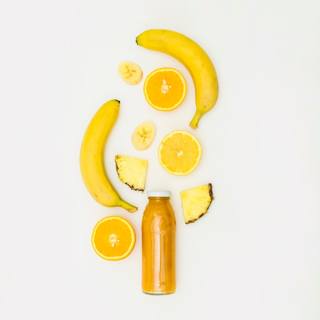 Banane; orange coupée en deux; couper l&#39;ananas sur la bouteille de smoothie sur fond blanc